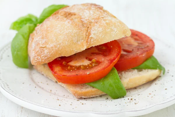 Бутерброд с помидорами и базиликом на тарелке — стоковое фото