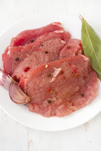 Carne di maiale cruda con aglio sul piatto — Foto Stock