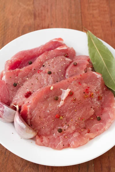 Carne di maiale cruda con aglio sul piatto — Foto Stock