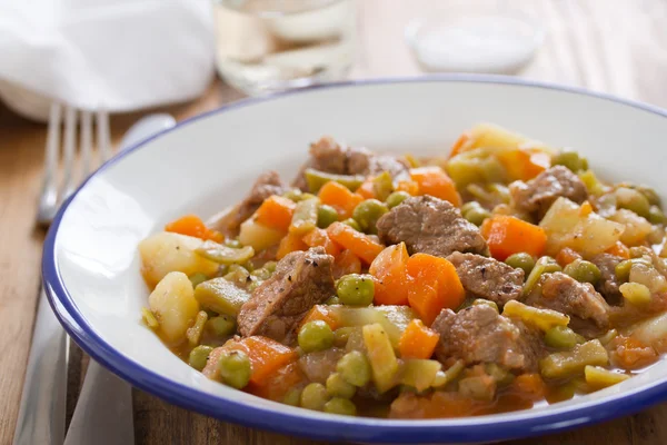М'ясо з морквою, горохом і картоплею на тарілці — стокове фото