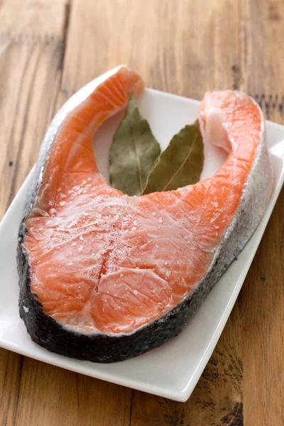 Salmon in ice on dish on brown wooden background — Stock Photo, Image