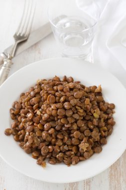 Beyaz ahşap zemin üzerinde beyaz plaka üzerinde kahverengi haşlanmış mercimek
