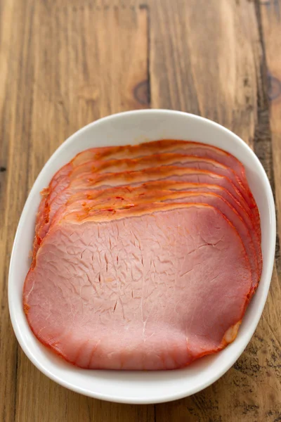 Ham on white dish on wooden brown background — Stock Photo, Image