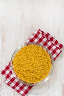 Pasta in bowl on napkin and white wooden background