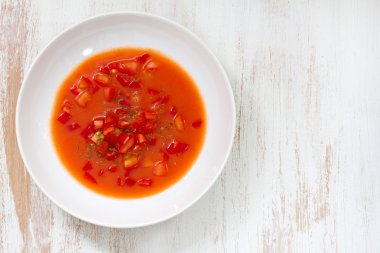 Cold tomato soup in white wooden background