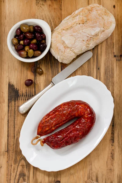 Salchicha ahumada sobre plato blanco sobre fondo marrón de madera — Foto de Stock