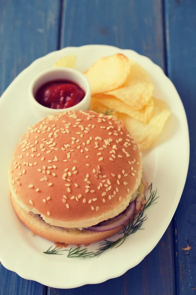 Hamburger with chips and tomato sauce on white dish — Stock Photo, Image