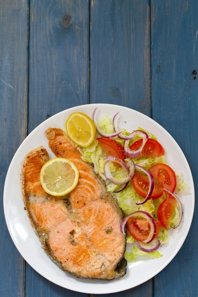 Gebratener Lachs mit Gemüsesalat und Zitrone auf weißem Teller — Stockfoto