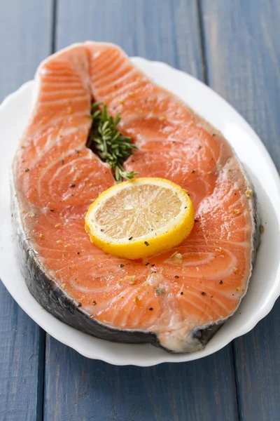 Fresh salmon with lemon on white dish on blue wooden background — Stock Photo, Image