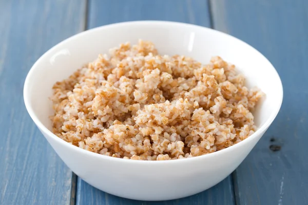 Boiled cereals in bowl on blue wooden background — Stock Photo, Image