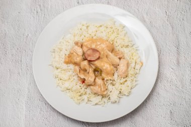 chicken stroganoff with boiled rice on white plate