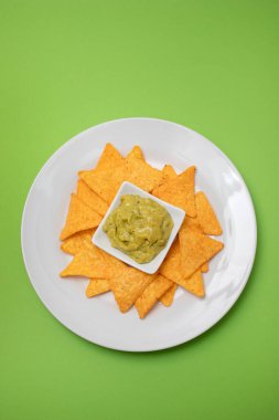 Meksika cipsi ve kâse ev yapımı avokado sosu ve beyaz tabakta limon.