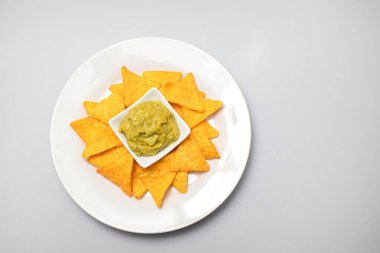 Meksika cipsi ve kâse ev yapımı avokado sosu ve beyaz tabakta limon.