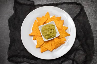 Meksika cipsi ve kâse ev yapımı avokado sosu ve beyaz tabakta limon.