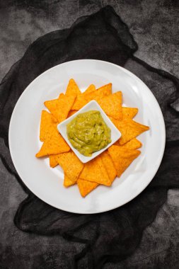 Meksika cipsi ve kâse ev yapımı avokado sosu ve beyaz tabakta limon.