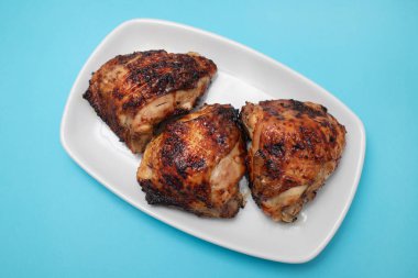 Beyaz tabakta ızgara tavuk budu.