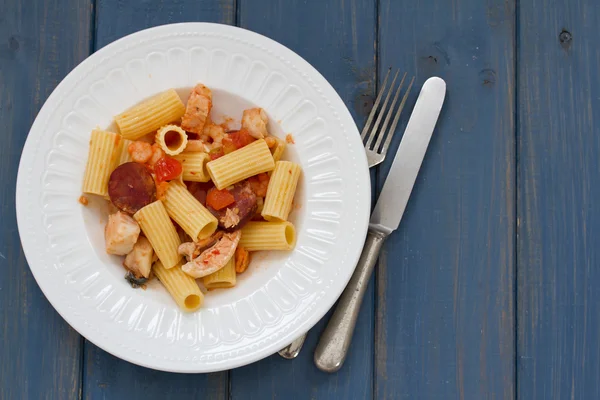 Pasta with dry tomato and smoked sausages on plate — Stock Photo, Image