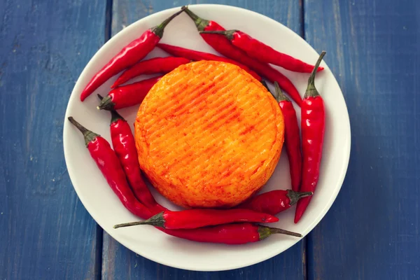 Spicy cheese with knife on blue wooden background — Stock Photo, Image