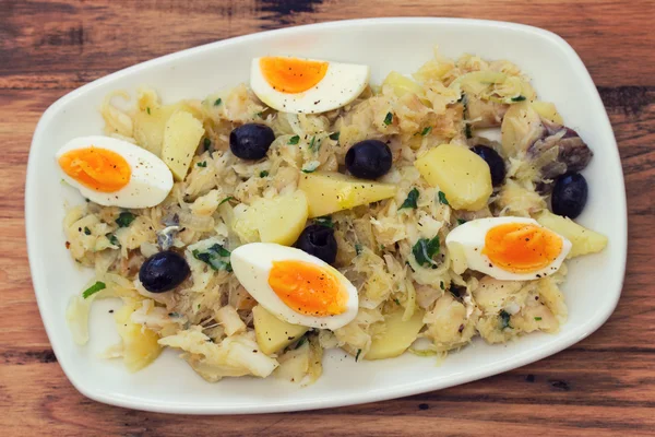 Bacalhau com legumes e azeitonas em prato branco — Fotografia de Stock