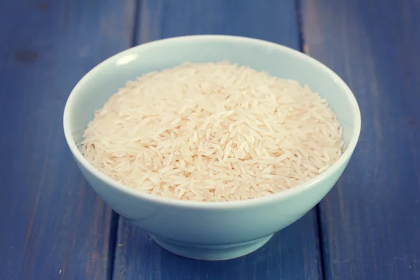 Raw rice on blue bowl — Stock Photo, Image