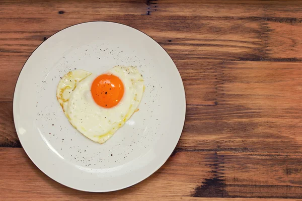 Fried egg heart on white plate — Stock Photo, Image