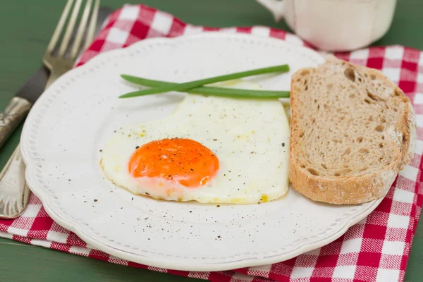 Fried egg heart with onion on white plate — Stock Photo, Image