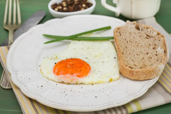 Fried egg heart with onion on white plate — Stock Photo, Image