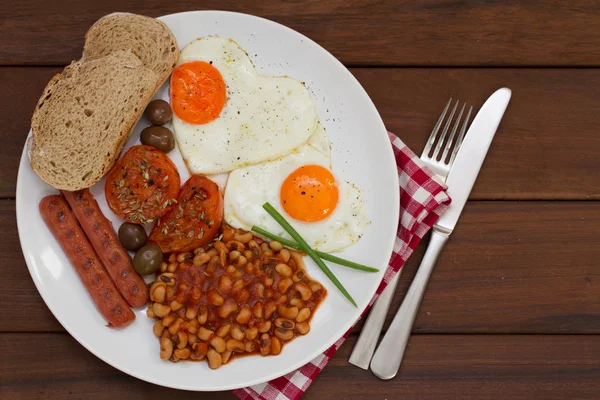 Fried eggs with bread, sausages and beans on white plate — Stock Photo, Image