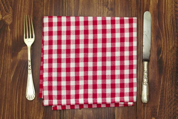 stock image fork with knife and napkin on brown wooden background