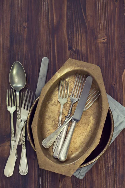 Forchette, cucchiai e piatto su fondo di legno marrone scuro — Foto Stock
