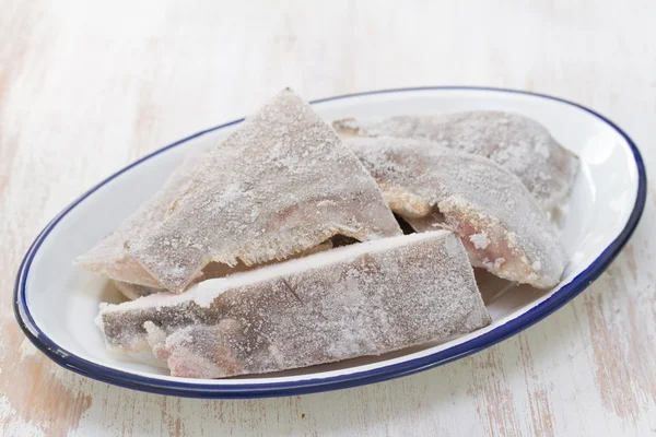 Pescado congelado en plato blanco en marrón —  Fotos de Stock