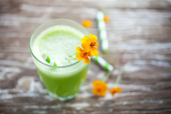 Зеленый сок с оранжевыми цветами — стоковое фото
