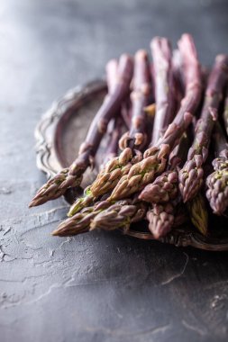 Koyu arkaplanda mor kuşkonmaz olan fotoğraf setini kapat. Resimler, yemek tarifleri sağlıklı yemek tarifleri ve aşçılık ilhamı ile ilgili temalar için uygun gurme içerikleri, rustik dokular ve yaratıcı gıda sunumunu gösteriyor.