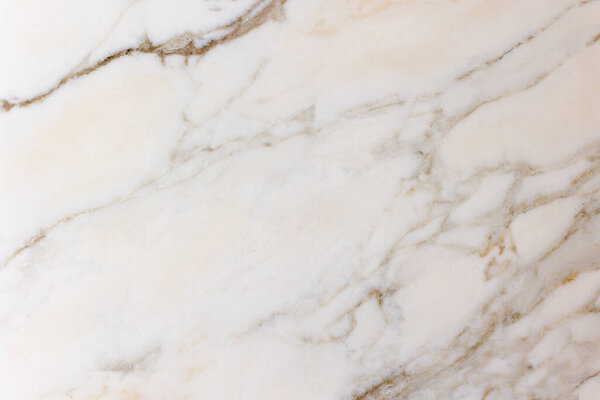 The image shows a close-up of a white marble surface with natural beige and gray veining. The organic lines create an elegant and minimal pattern, highlighting the refined texture of the stone.