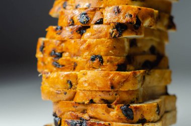 Beyaz arka planda sultanlı meyveli somun ve portakal aromalı parçalar, geleneksel meyve ekmeği.