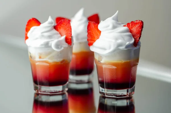 Colorful layered shots of drinks based on vodka, grenadine and orange juice decorated with whipped cream and pieces of strawberry in the shape of bunny ears, easter shots