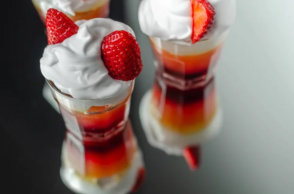 Colorful layered shots of drinks based on vodka, grenadine and orange juice decorated with whipped cream and pieces of strawberry in the shape of bunny ears, easter shots