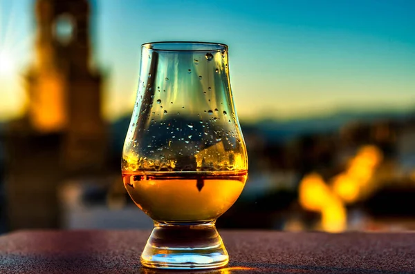 Expensive single malt whiskey in the rays of the setting sun, in the background a picturesque Spanish town with a church tower, relax with unique whiskey