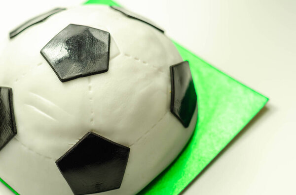 Football cake, sponge filled with frosting and raspberry jam, finished with soft icing and edible decorations, cake for a football player