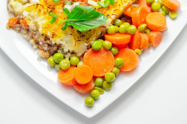 Shepherd\'s pie, tender minced lamb with garden veg in a hearty gravy beneath butter mash with carrots and green peas, traditional british meal