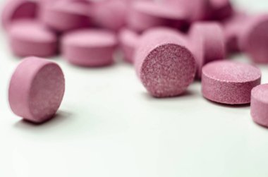 Beyaz arka plana saçılmış mor haplar, Acai üzümleri içeren gıda takviyeleri, ilaç.