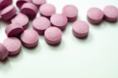 Beyaz arka plana saçılmış mor haplar, Acai üzümleri içeren gıda takviyeleri, ilaç.