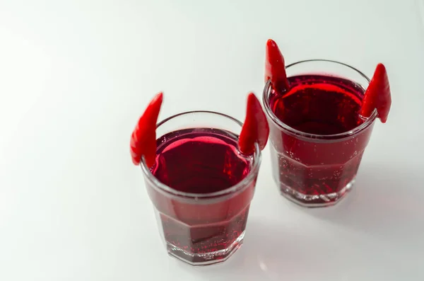 Drink shot prepared with vodka, grenadine and lemon juice decorated with bird eye chillies in the shape of horns, devils shot