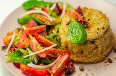 Eriyen çedar soslu füme mezgit balığı keki ve karışık salata, deniz ürünleri.