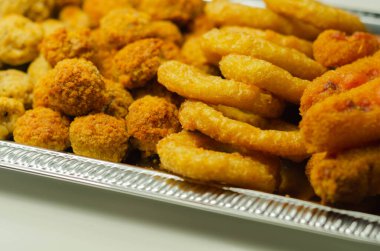 Güneyin kızarmış tavuğu, soğan halkaları ve gümüş tepside servis edilen mozzarella çubuğu, parti ısırıkları.