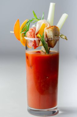 Kokteyl bardağının üstünde küçük bir aperatifle ilginç dekorasyonlu Bloody Mary, tazelik içeceği.