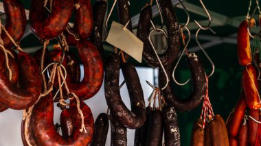 Tipik İspanyol sosisleri gıda pazarında bir köy tezgahında asılı duruyor, geleneksel et ürünleri.