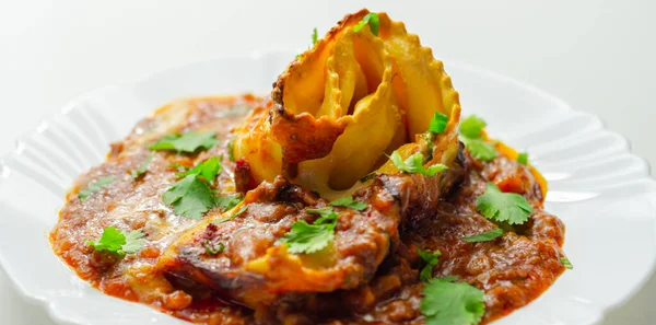 Dört peynirli ravioli makarna dilimlenmiş biftek, Chianti kırmızı şarap, sarımsak ve otlu ragu, ve üzerine pekorino peynirli ekmek kırıntısı ve taze maydanoz, ravioli tacıyla bitirilmiş beşamel sosu.