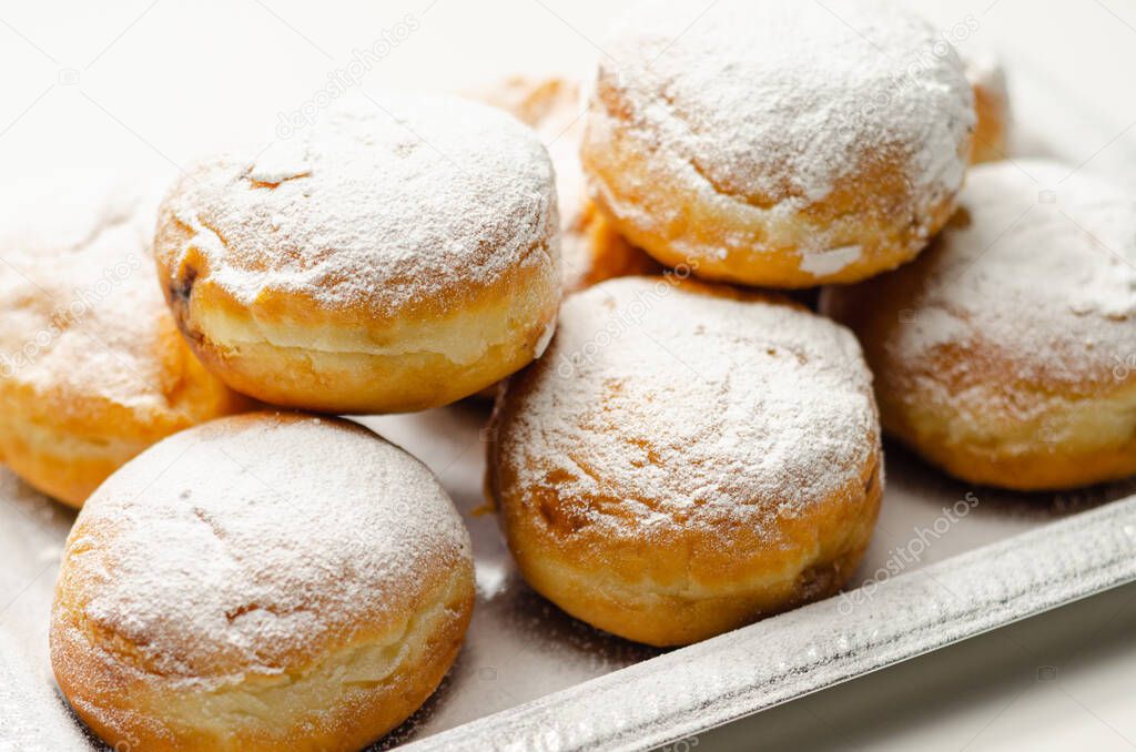Berliner Pfannkuchen, a German donut, traditional yeast dough deep fried filled with chocolate cream and sprinkled with powdered sugar, sweetness on a silver tray