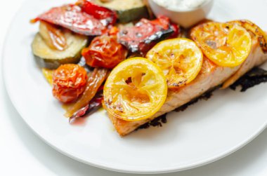 Kızarmış sebzeli ızgara somon filetosu, salatalık ve dereotu sosu, sağlıklı yiyecekler.